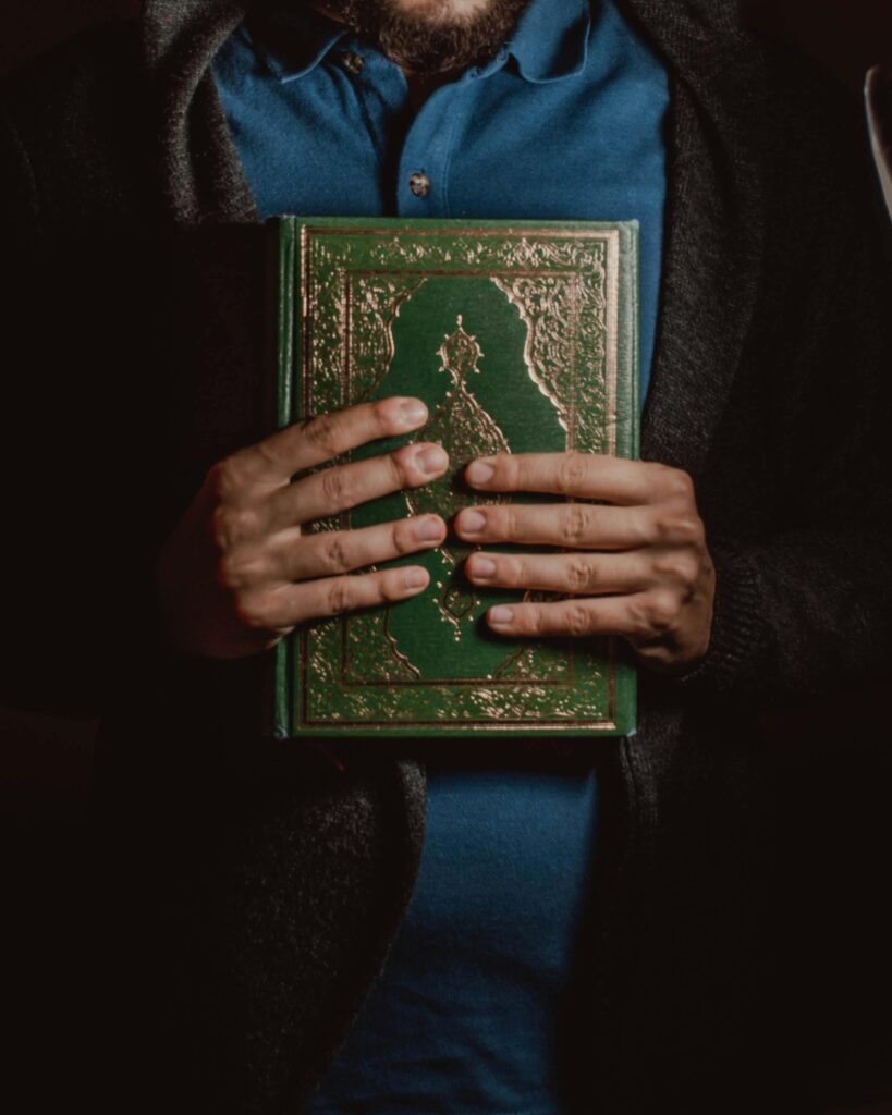 A person holds a Quran, showcasing its intricate cover, symbolizing reverence and religious devotion.